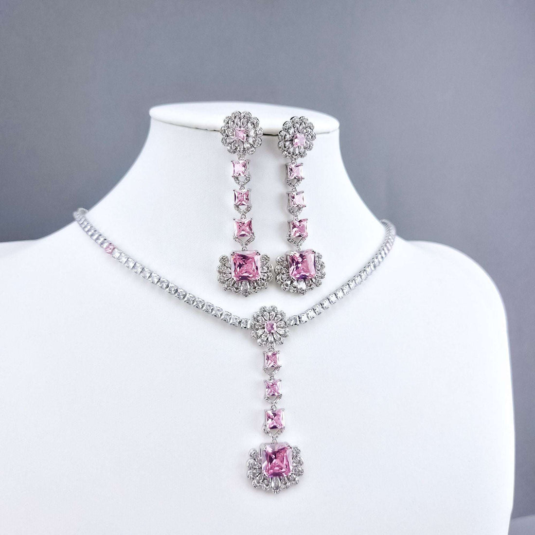 Pink crystal necklace with a pendant and long earrings on a white bust