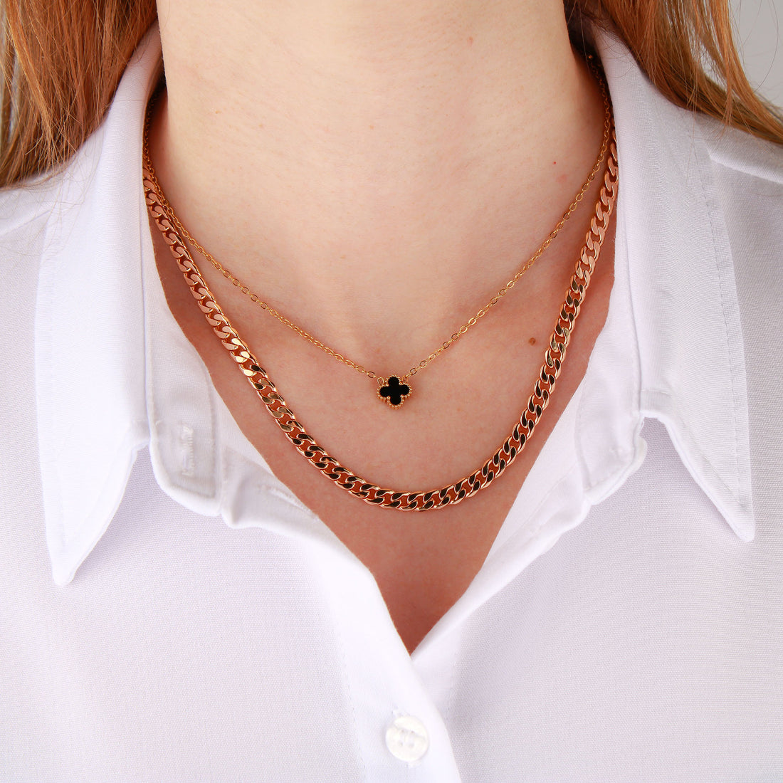 Model in a white shirt wearing the black clover pendant and a chunky chain