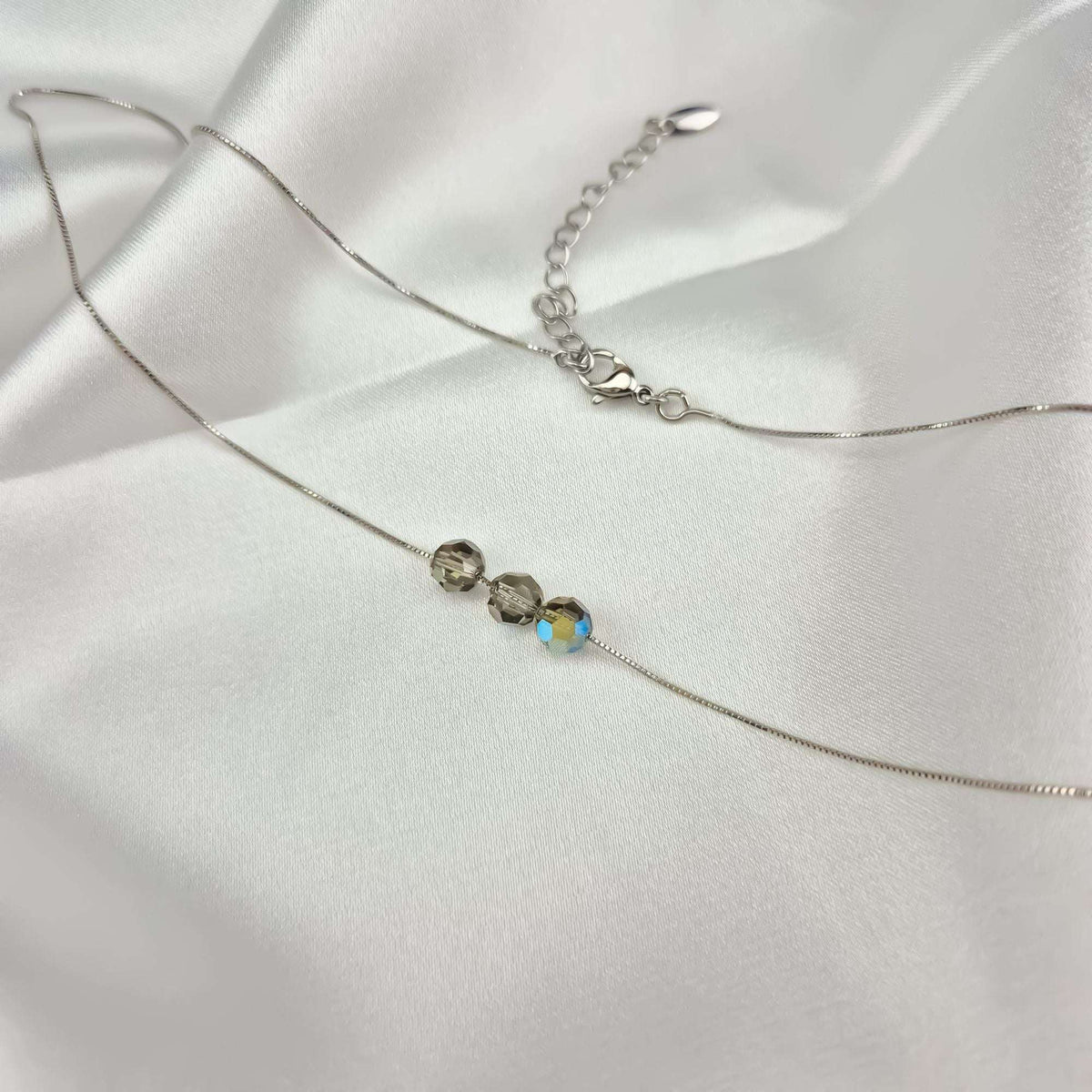 Venetian chain necklace with three crystals and an adjustable chain on white satin