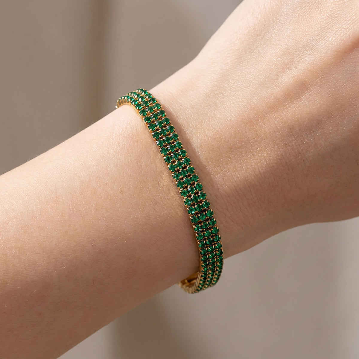 Gold-plated bracelet with three rows of green cubic zirconia on a woman's wrist