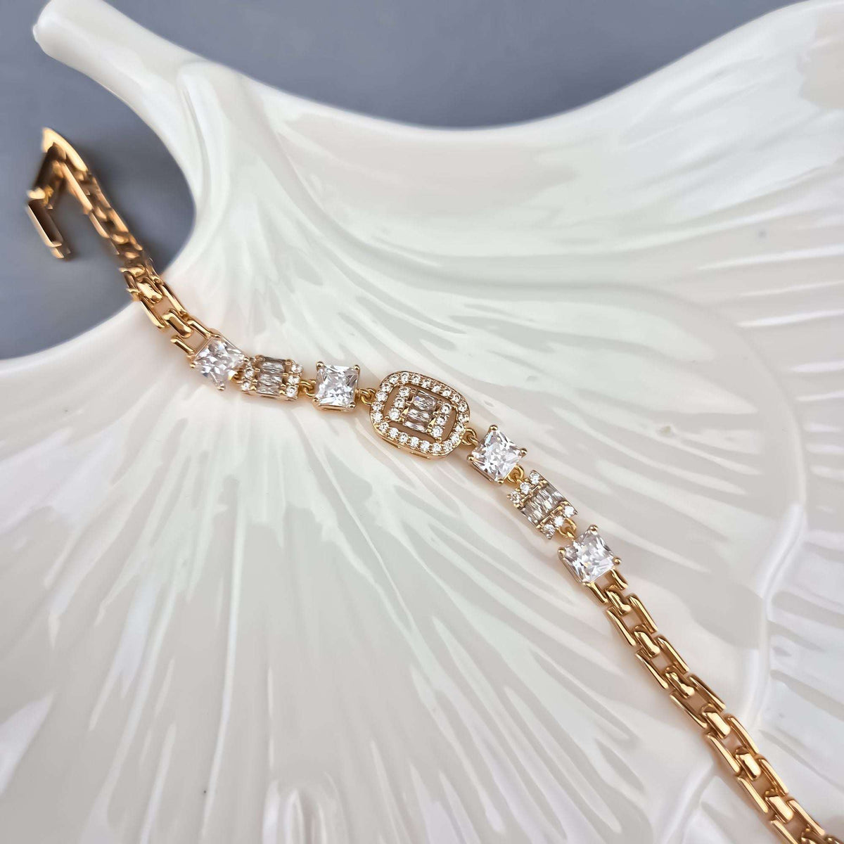 Cubic zirconia bracelet on a white ceramic leaf dish, close-up of the links
