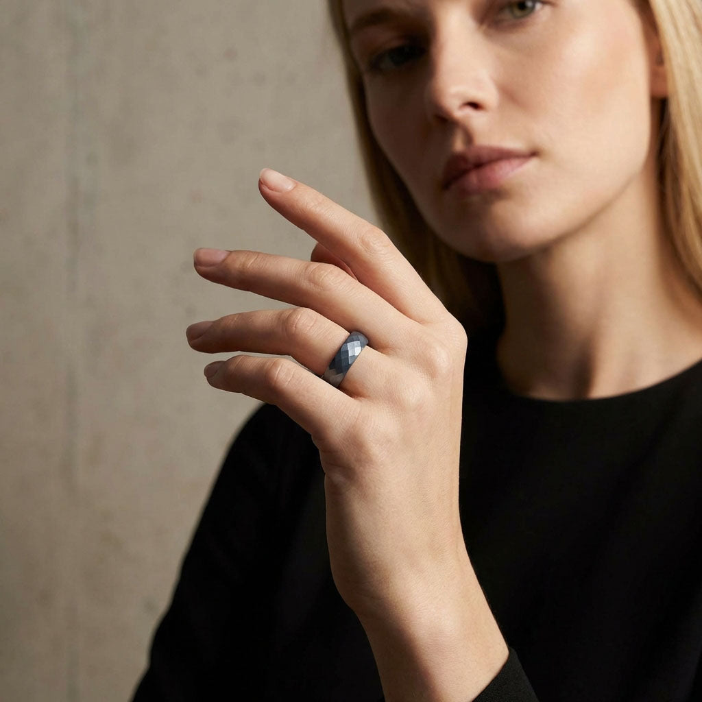 Blue ceramic ring on a blonde woman's finger against a pale concrete wall