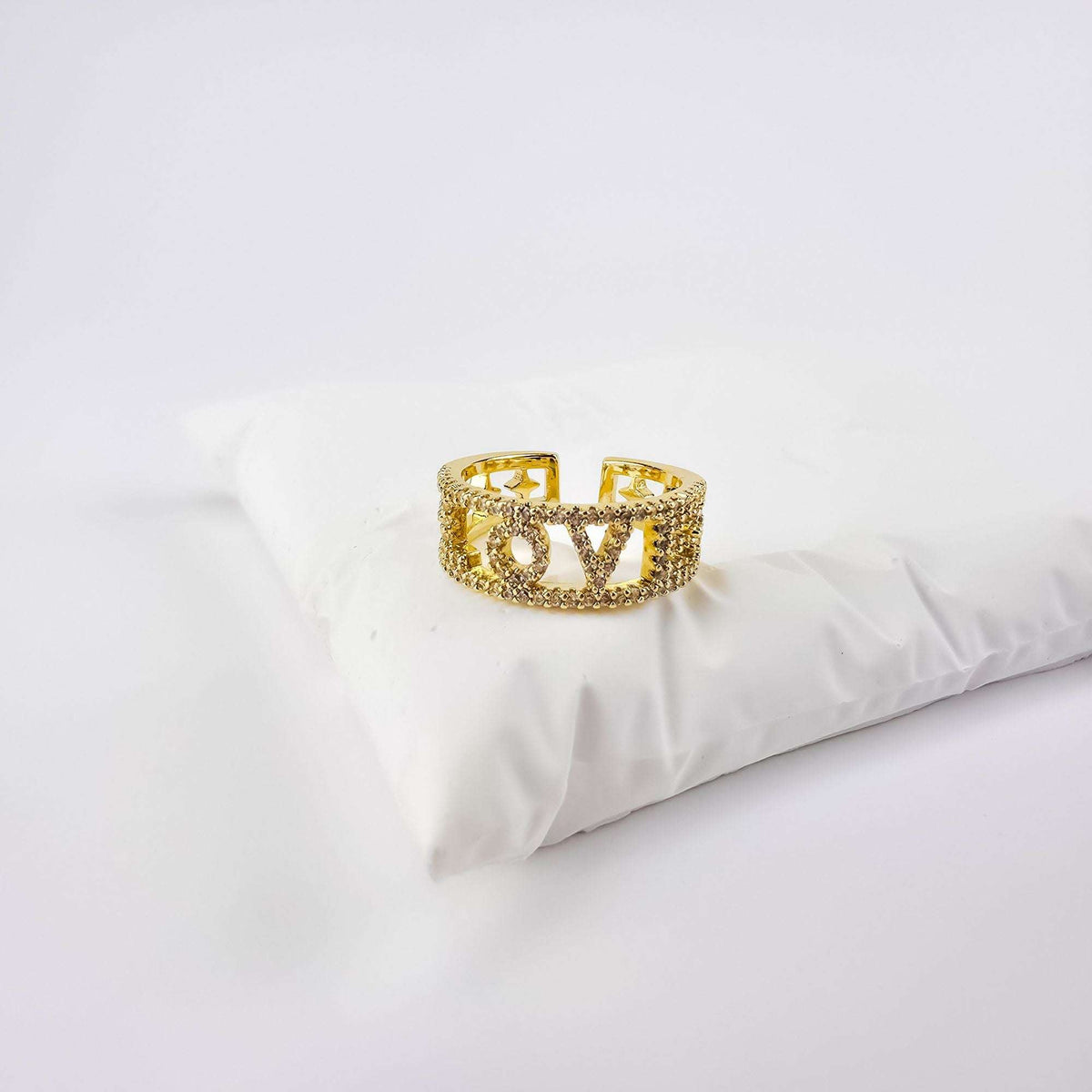 Gold-plated LOVE ring with cubic zirconia on a white fabric cushion