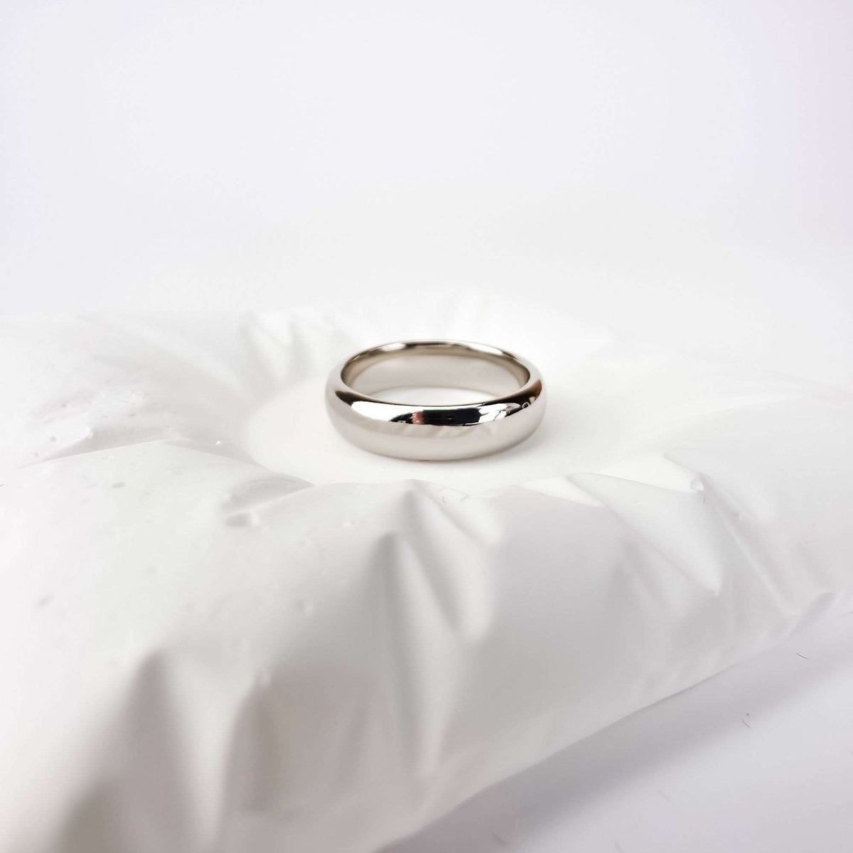 Platinum-plated ring with a mirror shine on white fabric, side angle