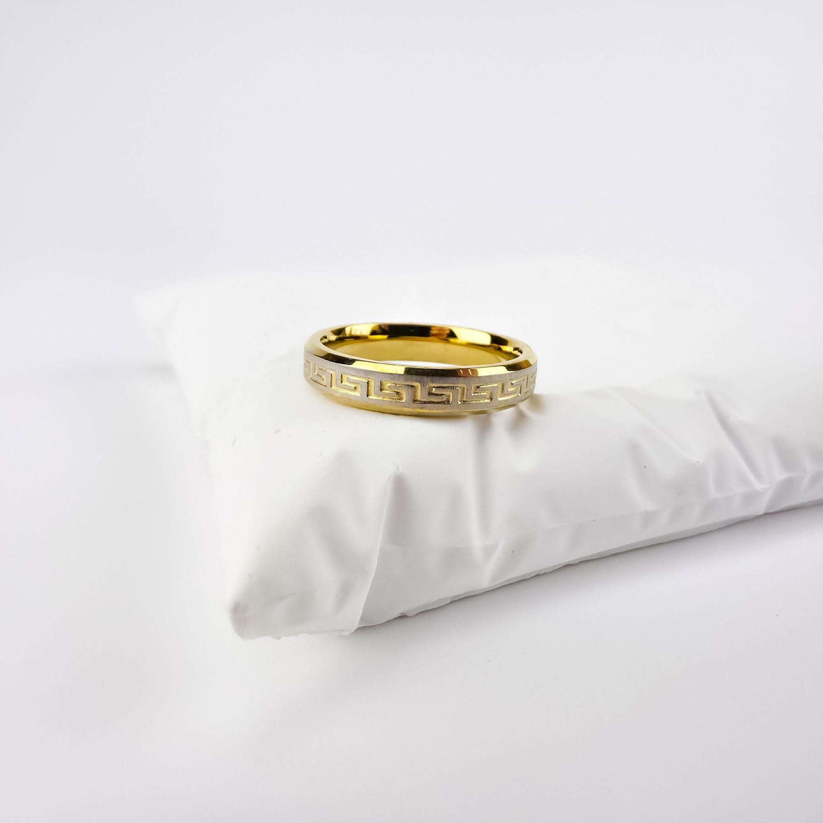 Greek key ring on a white cushion, gold-plated with a silver-tone stripe