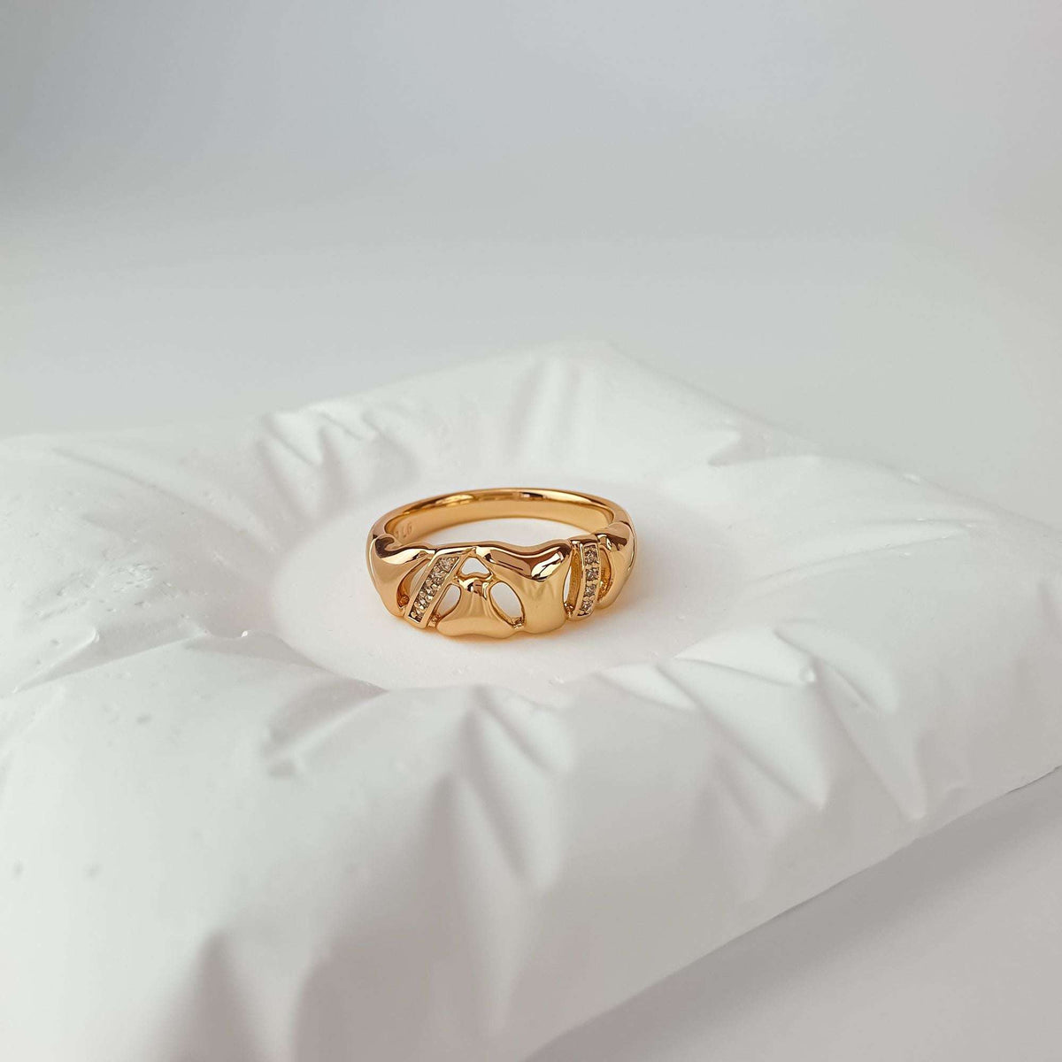 Gold-plated ring with wavy cut-outs and two rows of tiny crystals on white