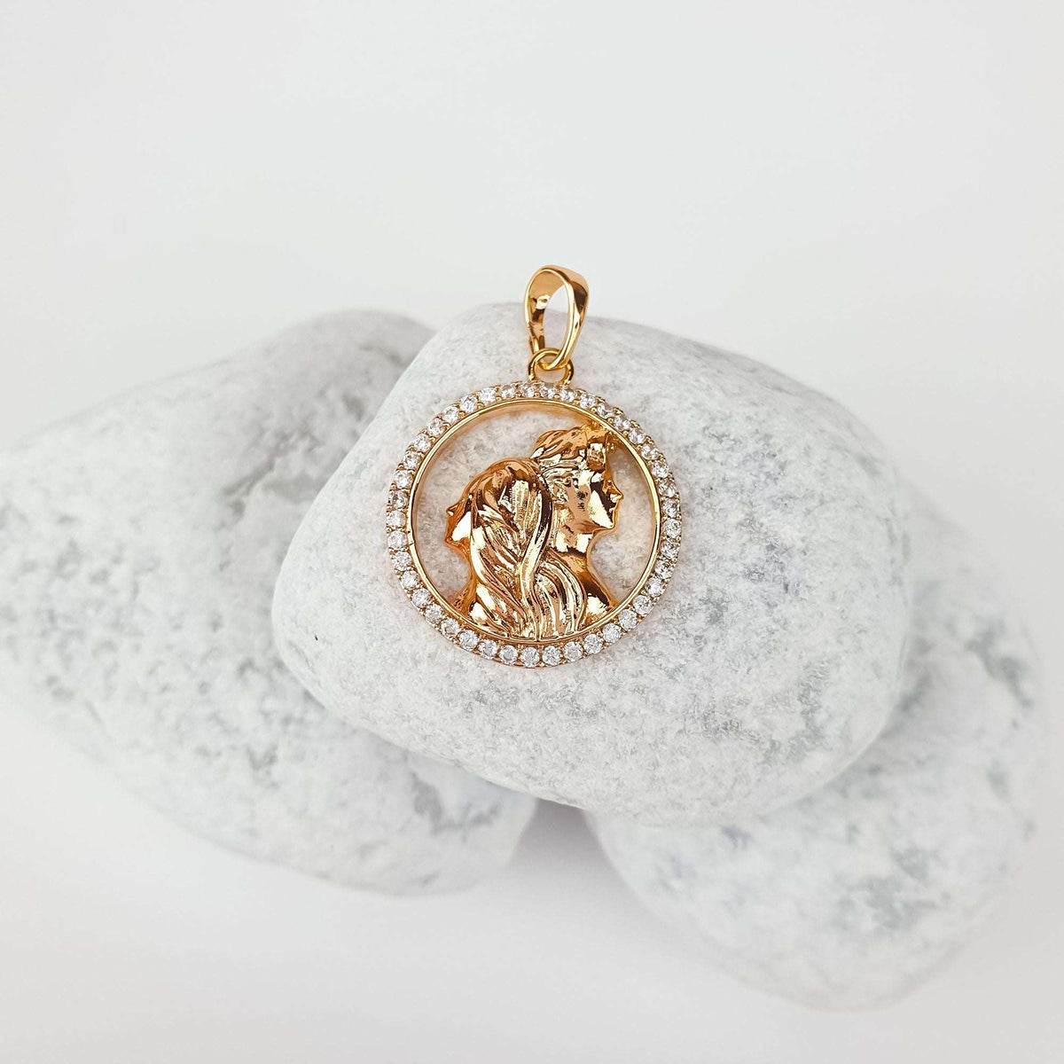 Couple silhouette pendant at an angle on pale pebbles, sparkling cubic zirconia border