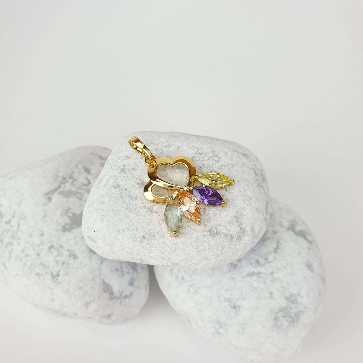 Gold-plated hearts pendant with yellow and violet stones on white pebbles