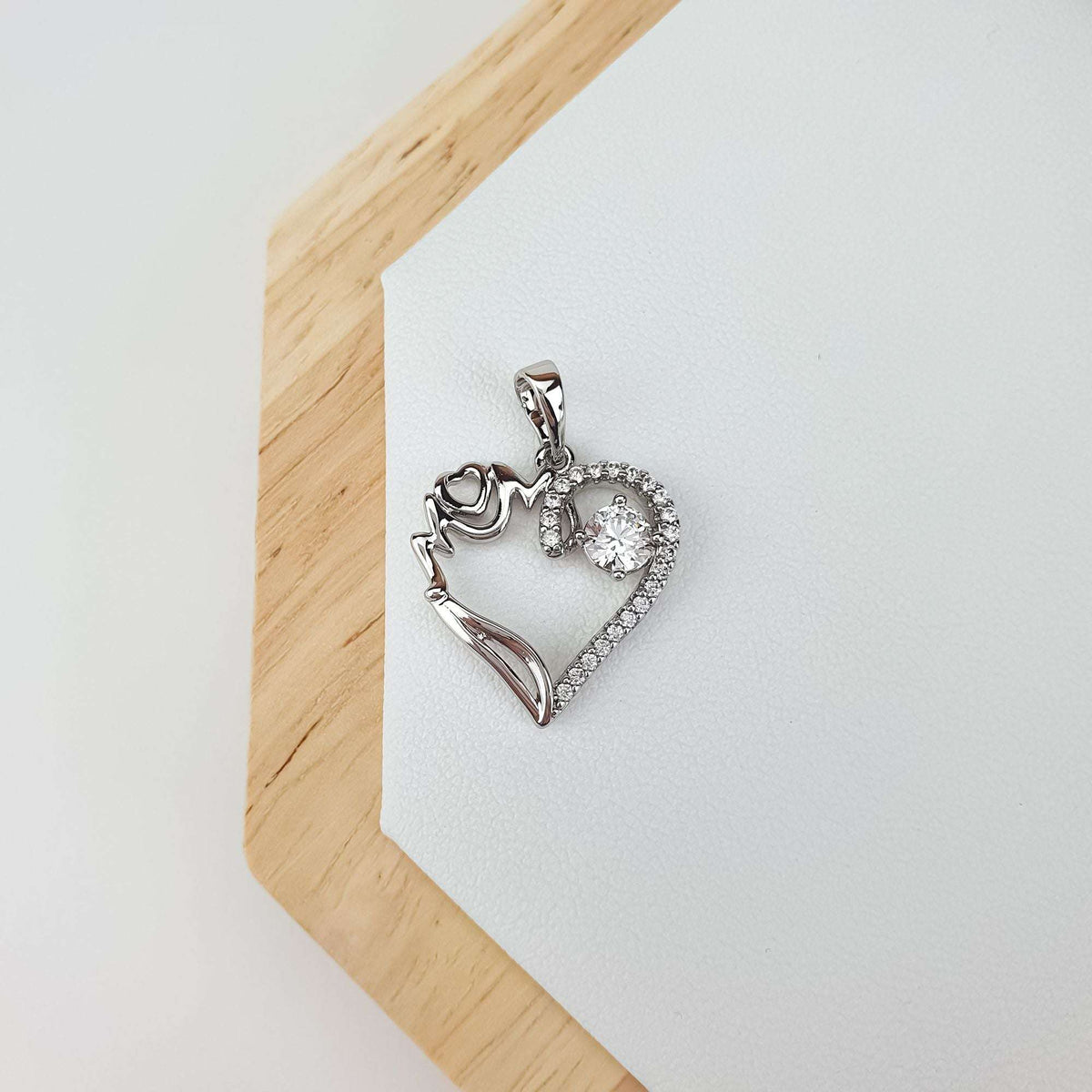 Silver-tone Mom pendant on a wooden stand, heart edge set with cubic zirconia