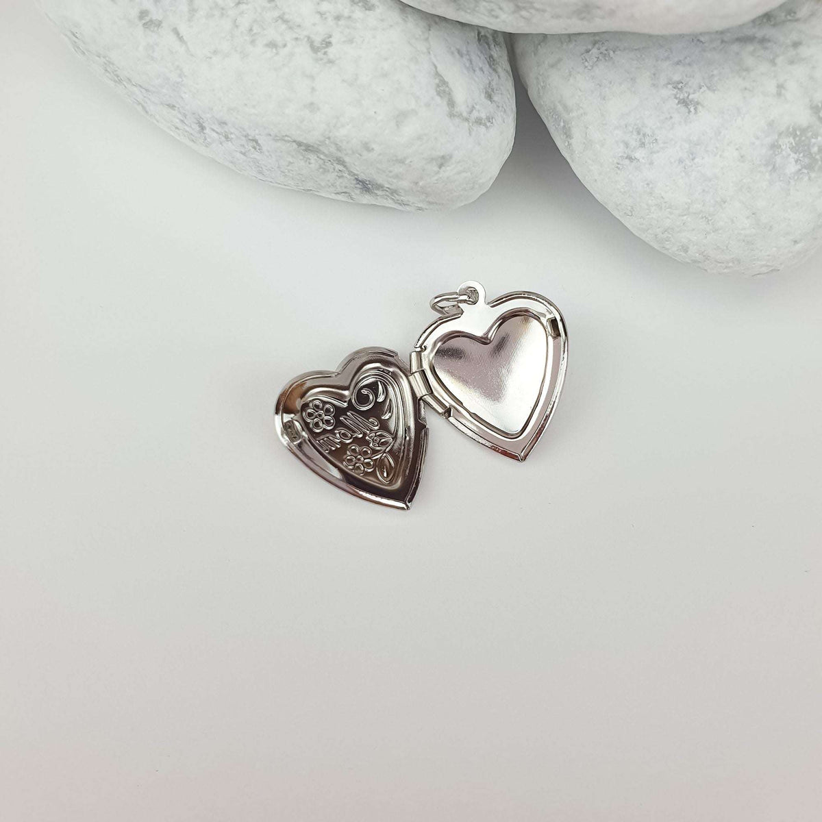 Silver-tone heart locket opened, showing the raised Mom inscription and space for a photo