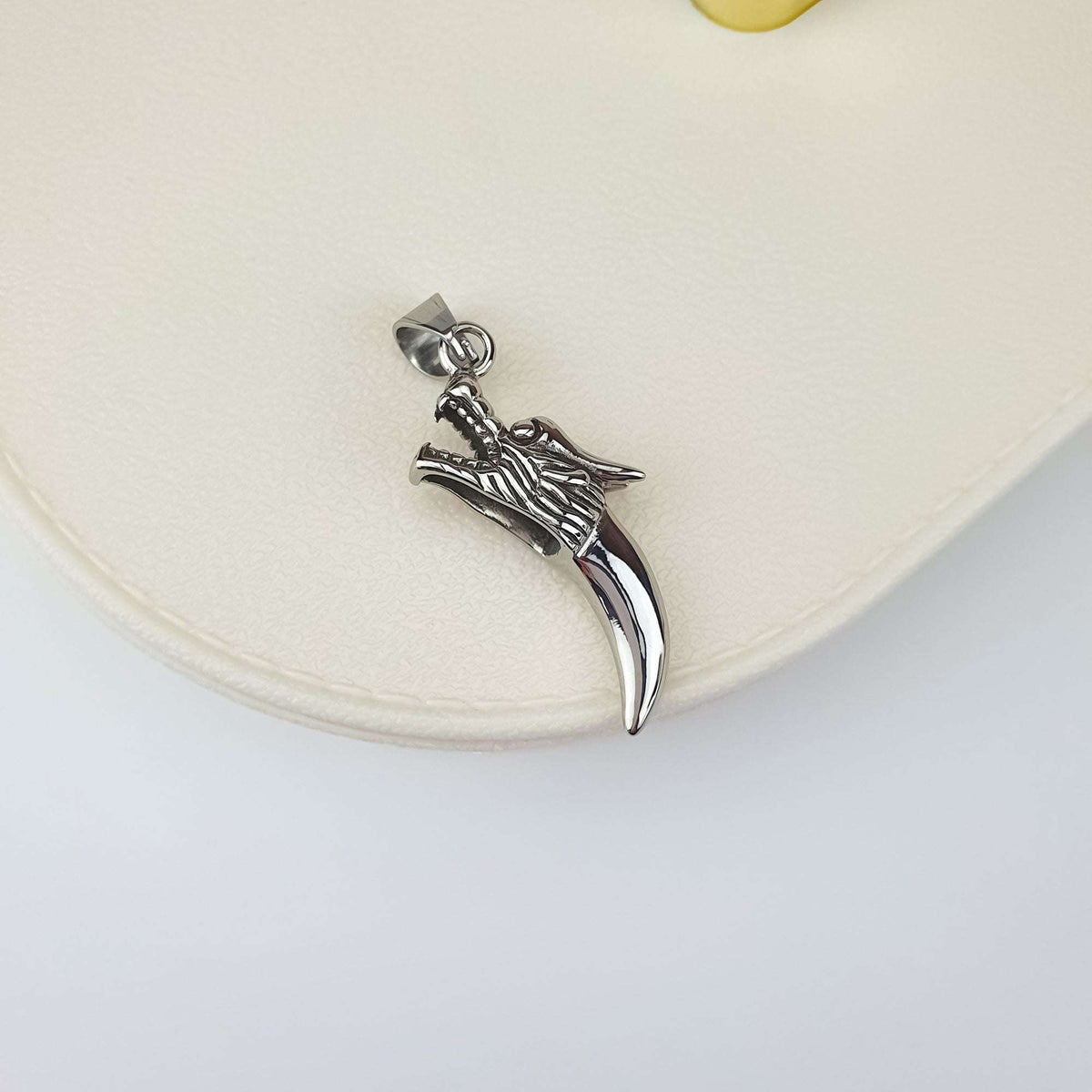 Steel wolf head and fang pendant on a light background