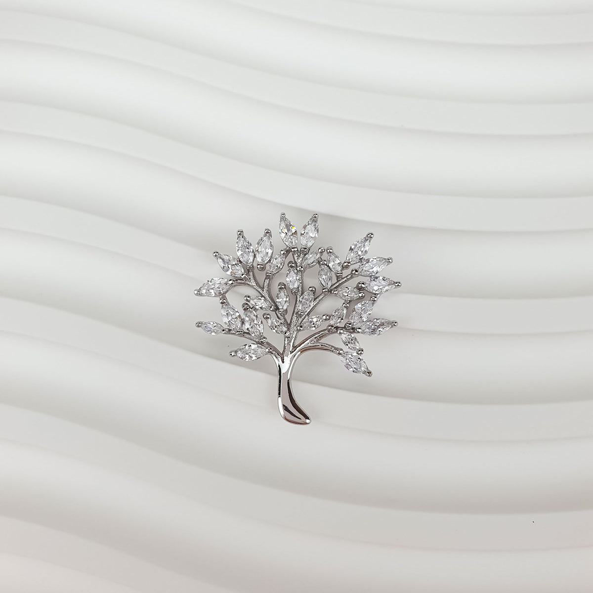 Platinum-plated tree of life pendant with cubic zirconia on a light wavy background
