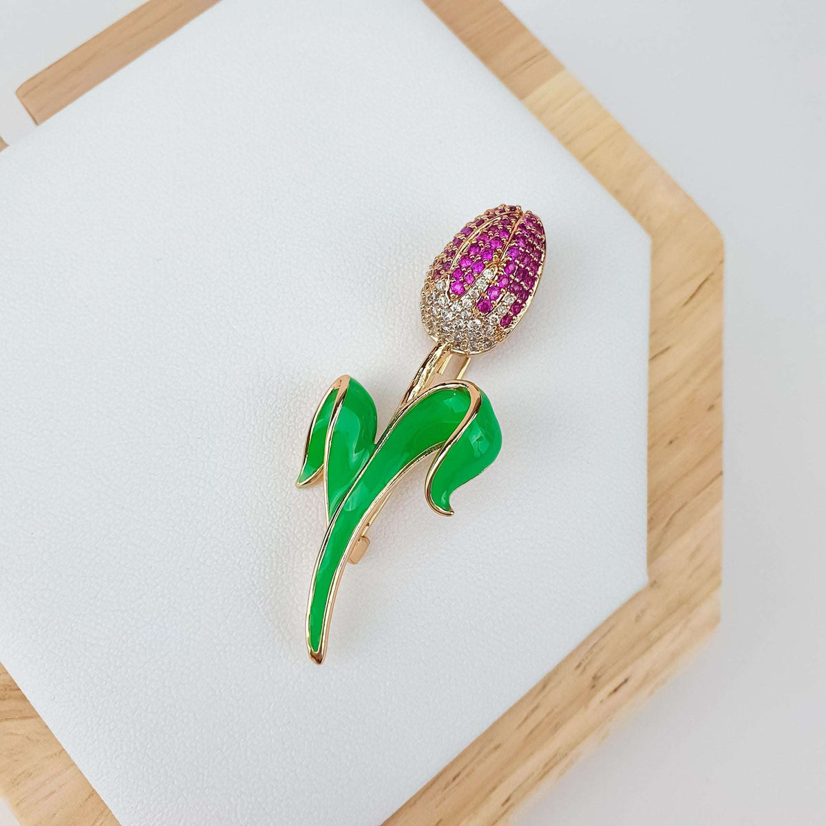 Tulip brooch at an angle on a white stand in a wooden frame