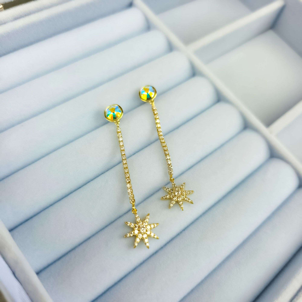 Gold-plated star earrings in a jewellery box, sparkling row of crystals