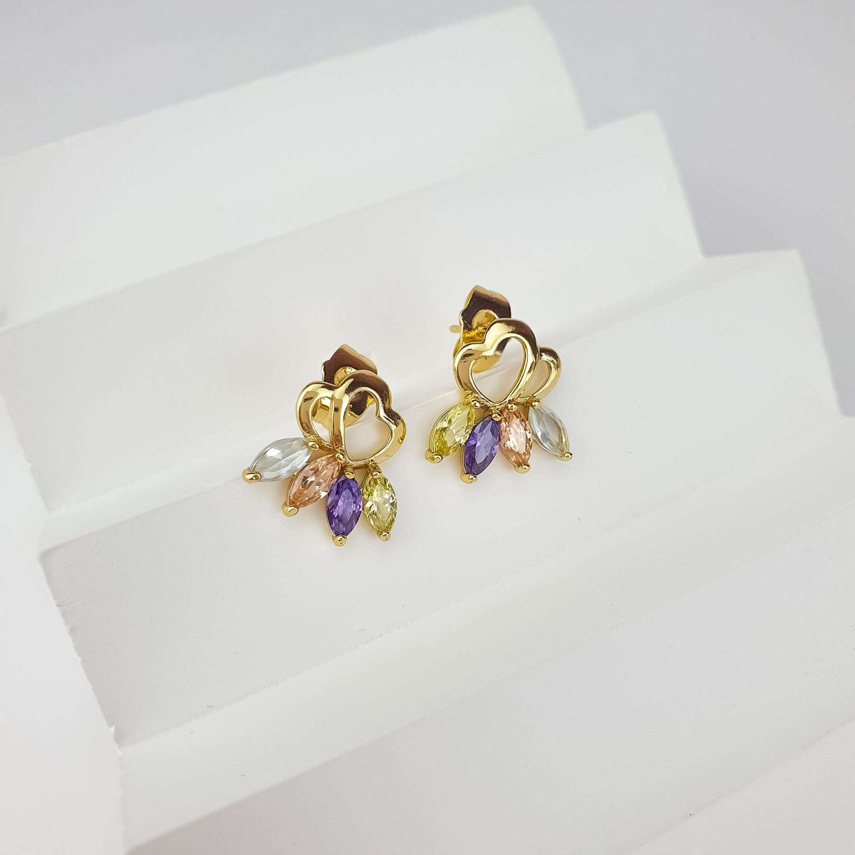 Heart stud earrings at an angle on a white stand, pastel marquise cubic zirconia