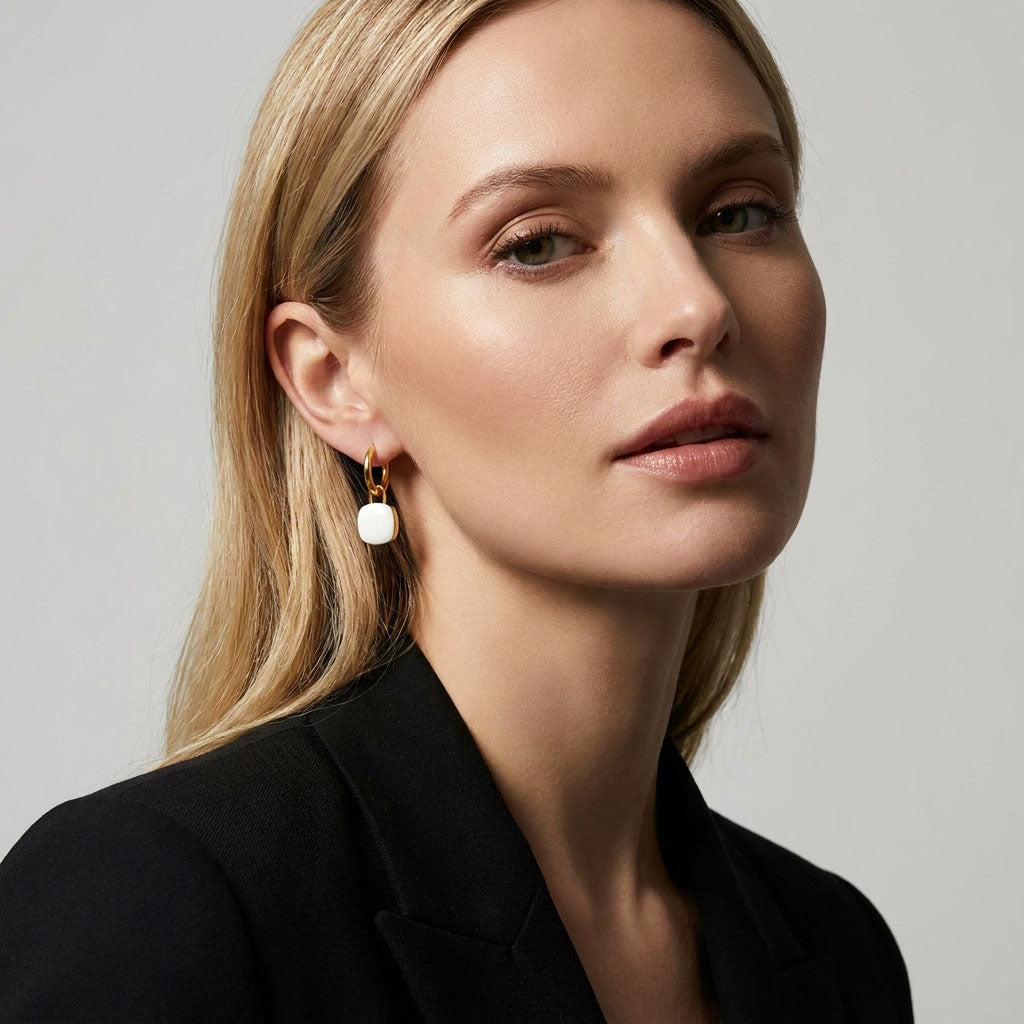 Blonde woman in a black jacket wearing a gold-plated hoop with white enamel charm