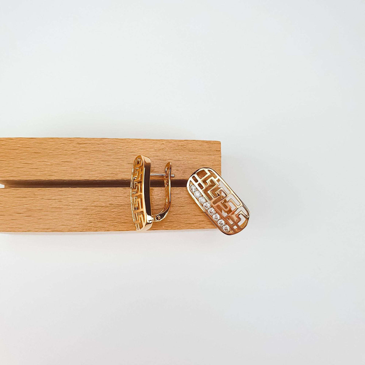 Rectangular Greek meander cut-out earrings with cubic zirconia on a wooden stand