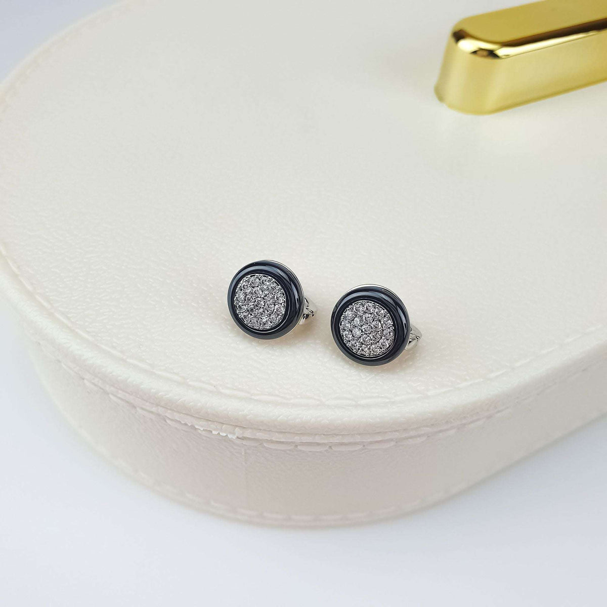 Compact round black ceramic earrings with cubic zirconia on a light gift box