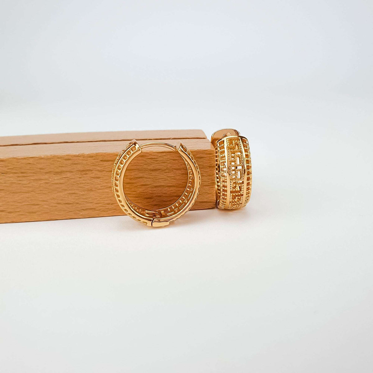Gold | Greek pattern earrings on a wooden stand, clasp and side profile visible