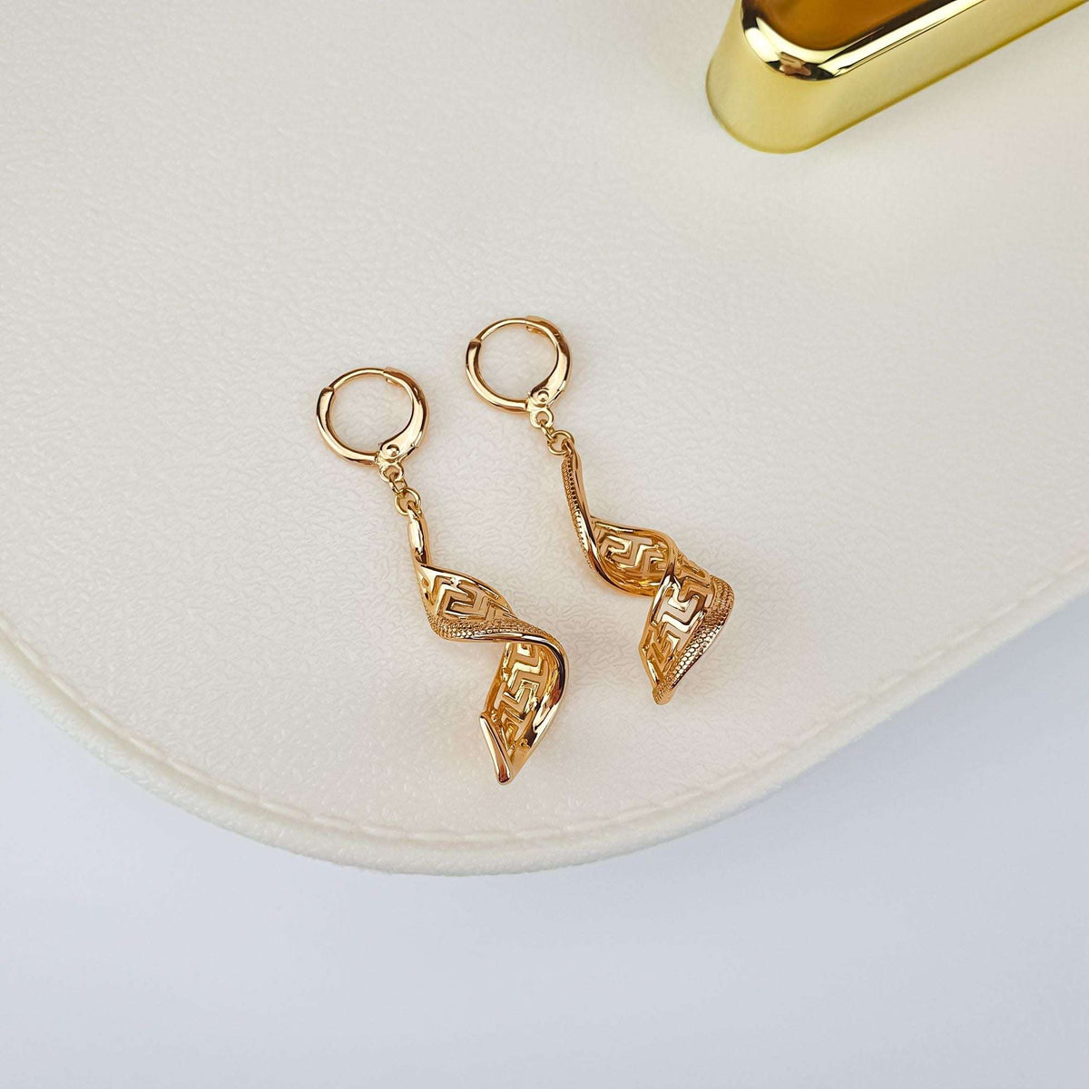 Gold-tone spiral earrings on a cream gift box