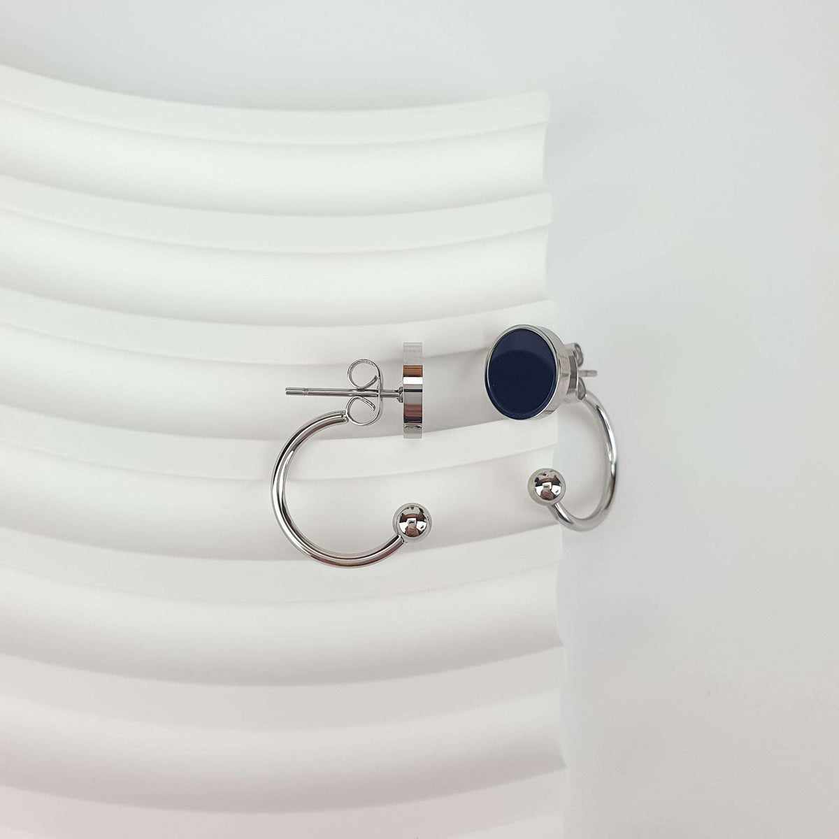 Two-in-one earrings taken apart: push-back stud, half-circle with ball, enamel circle