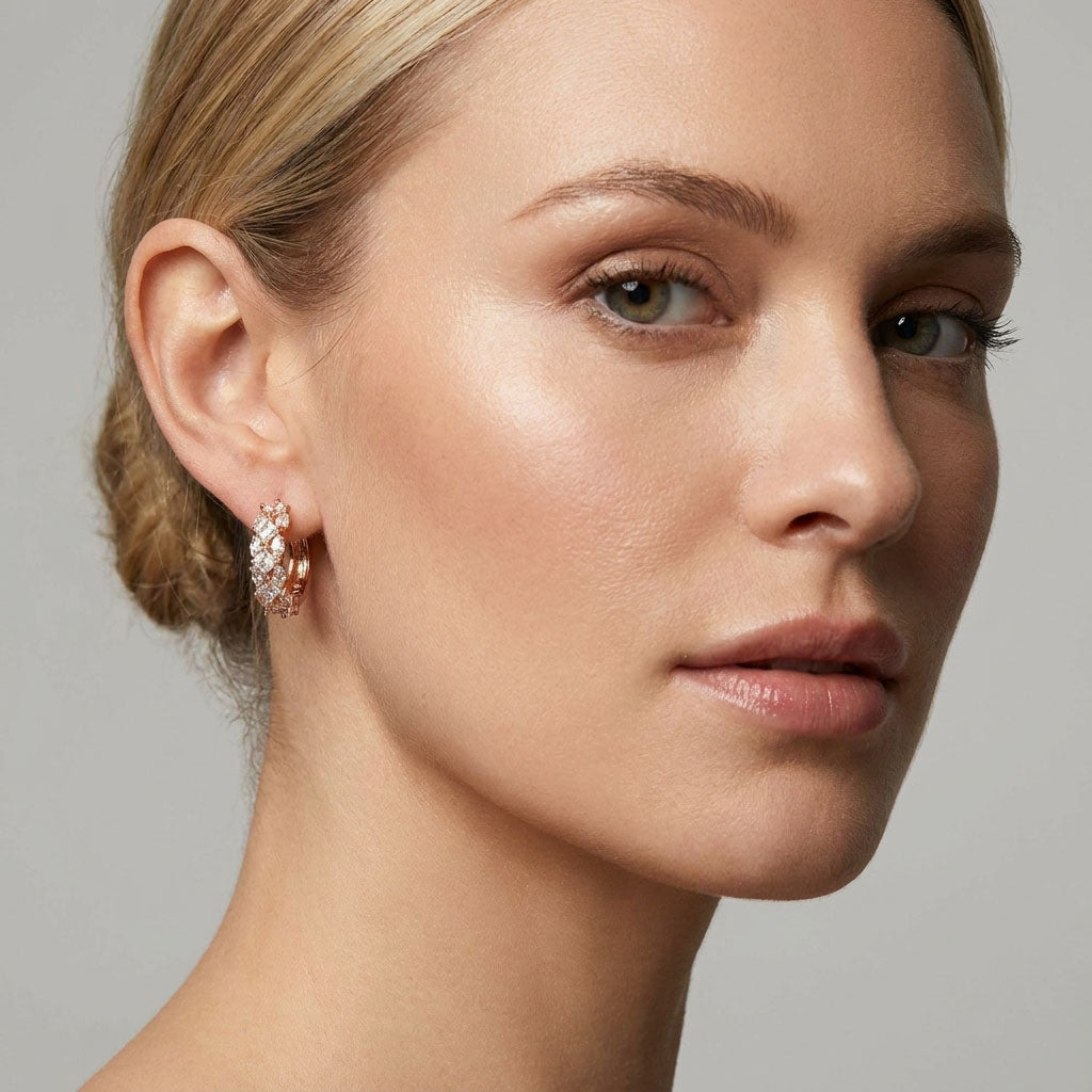 Gold-plated hoop earring with clear cubic zirconia on a model's ear, close-up