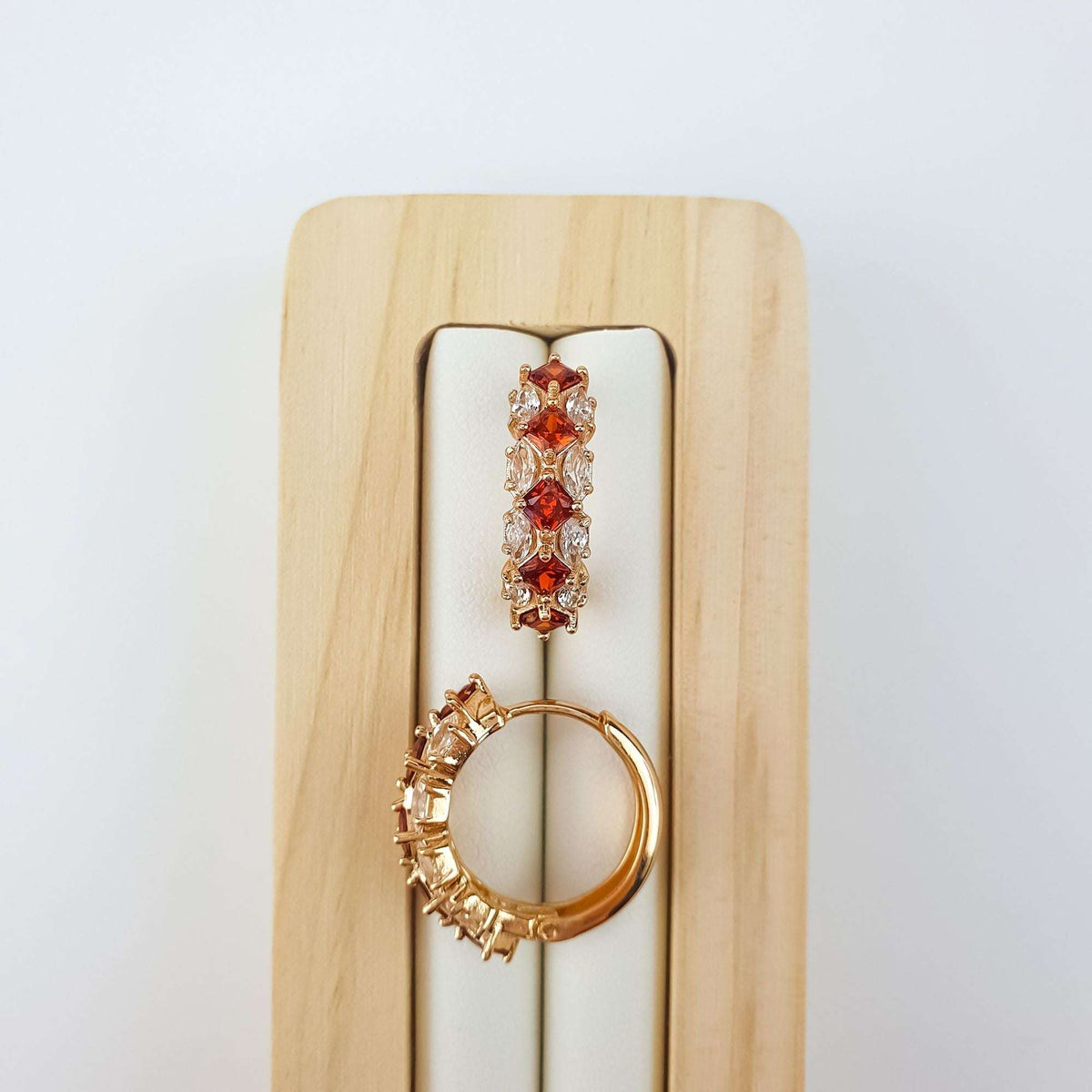 Red | Red stones close up on a wooden stand, second earring shows the hinge