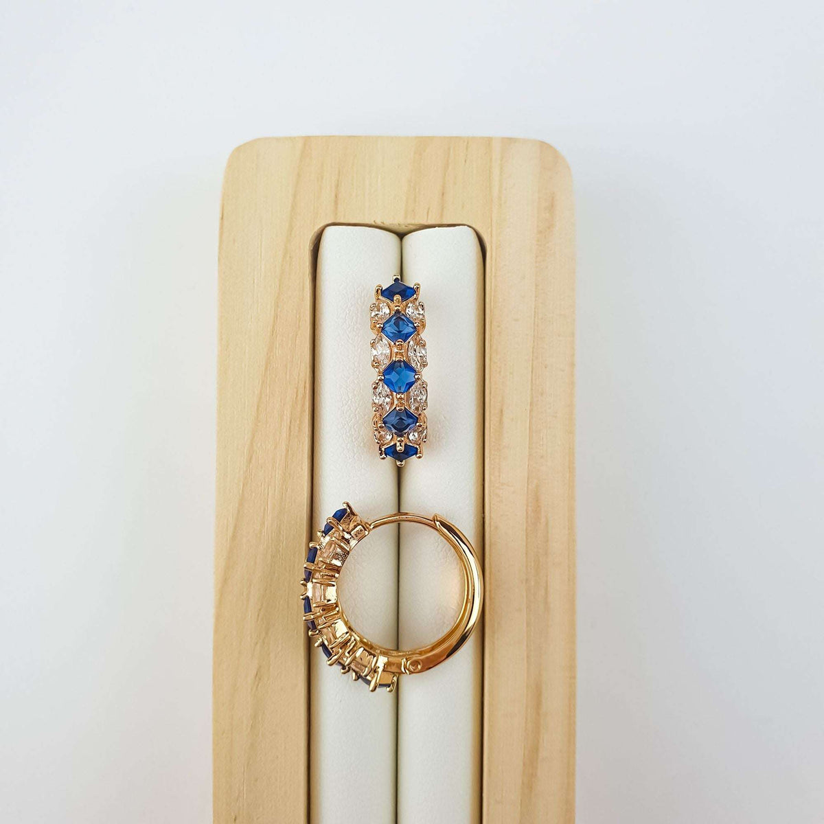 Blue | Deep blue stones close up on a wooden stand, second earring turned sideways