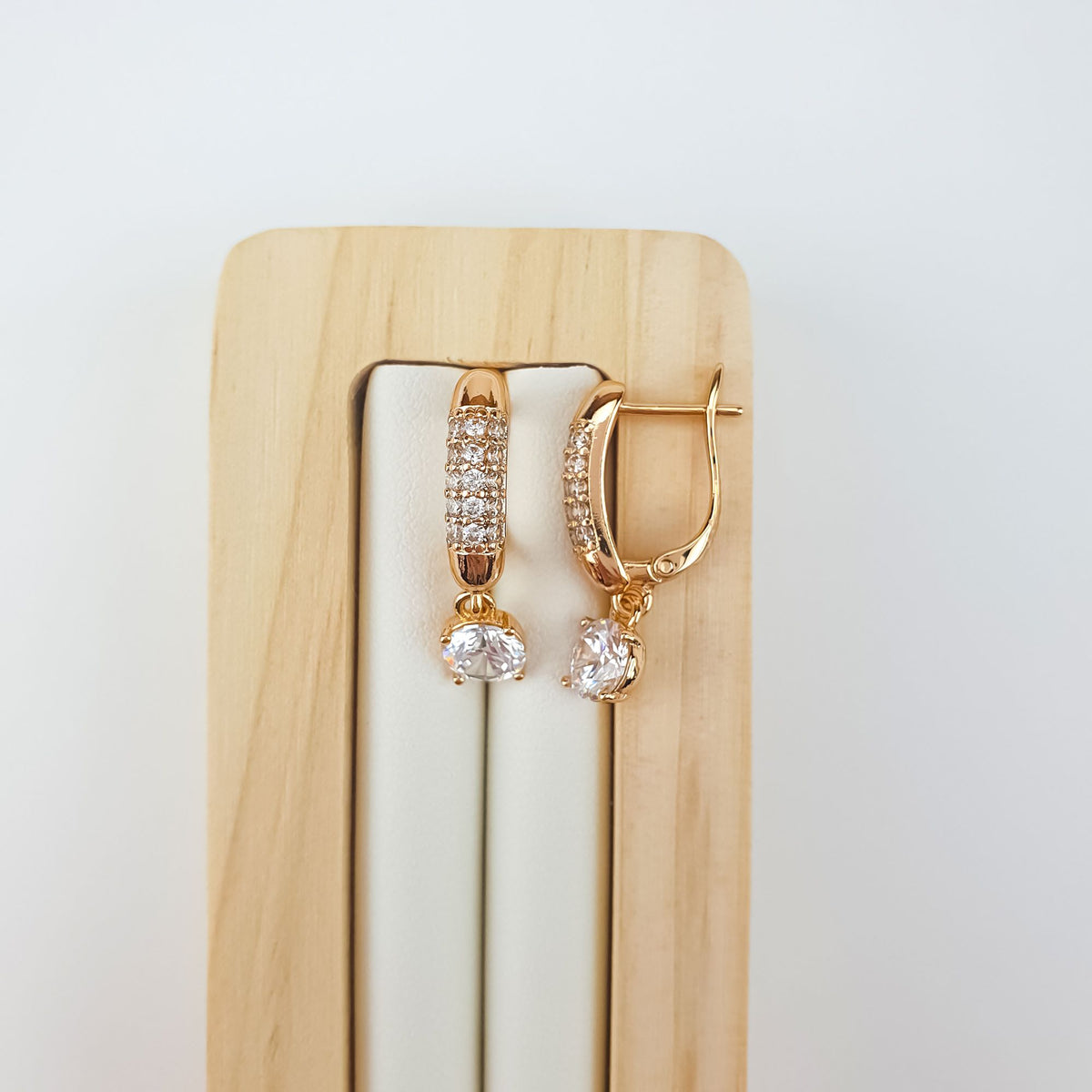 Pair of earrings with rows of stones on a light wooden stand