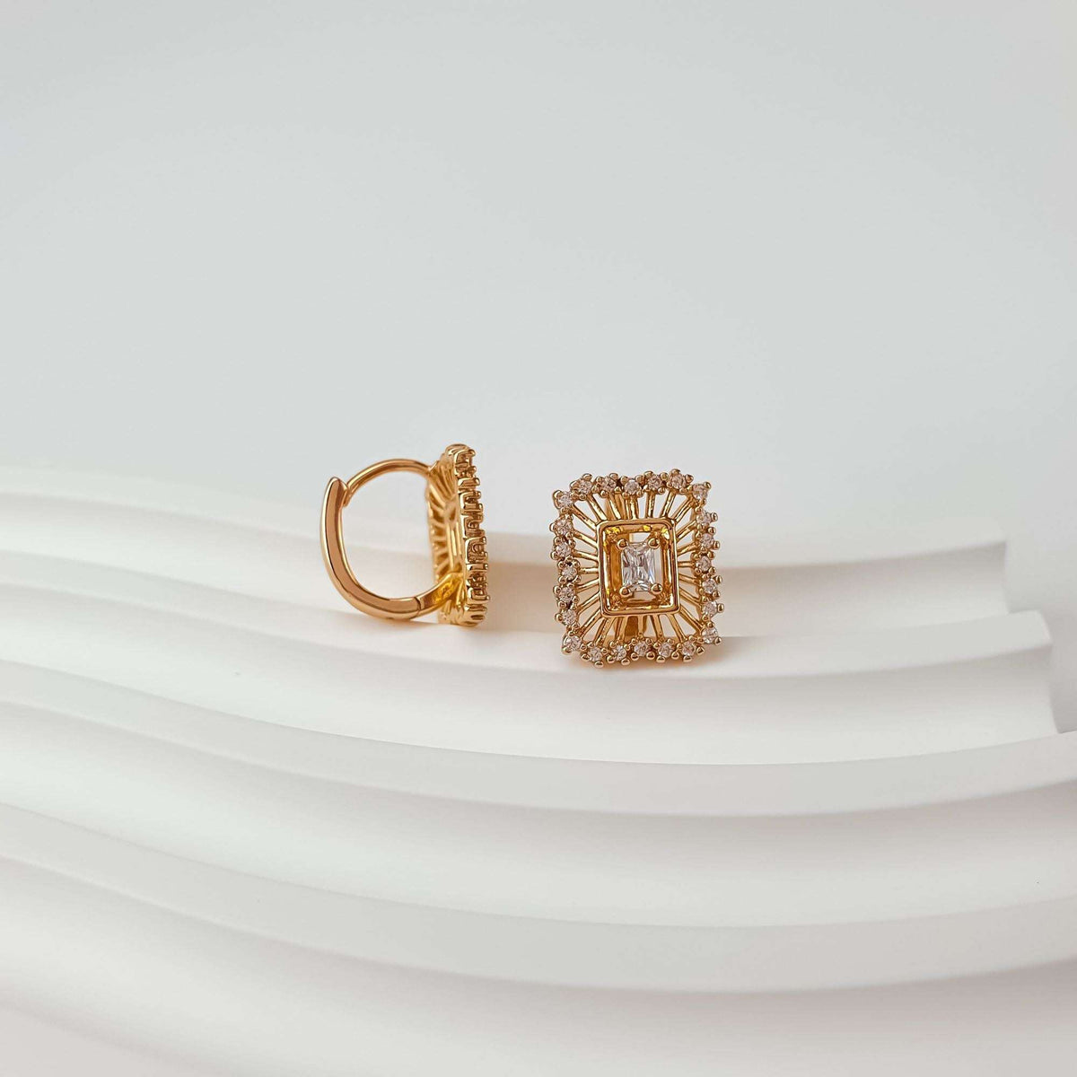 White rectangular stone in a gold-plated starburst frame, second earring in side view