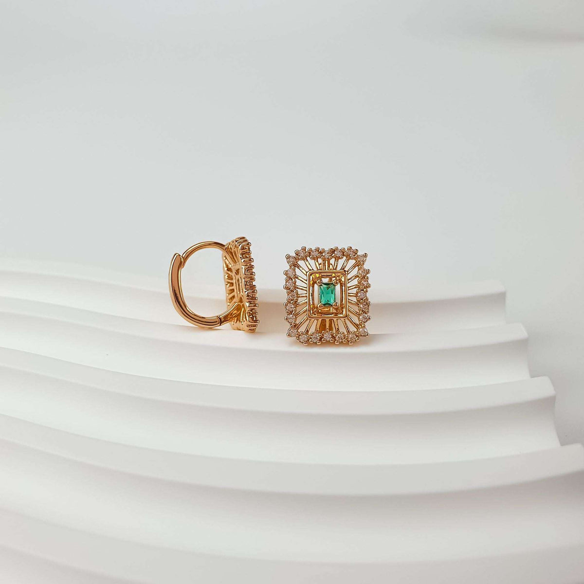 Green rectangular cubic zirconia in a gold-plated starburst frame, second earring beside it