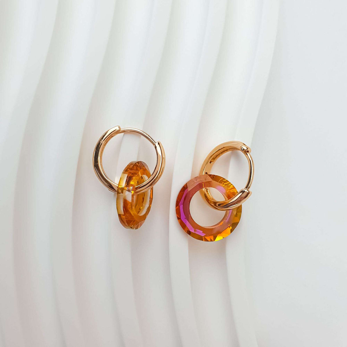 Orange crystal ring earrings on white fabric showing the depth of the cut stone