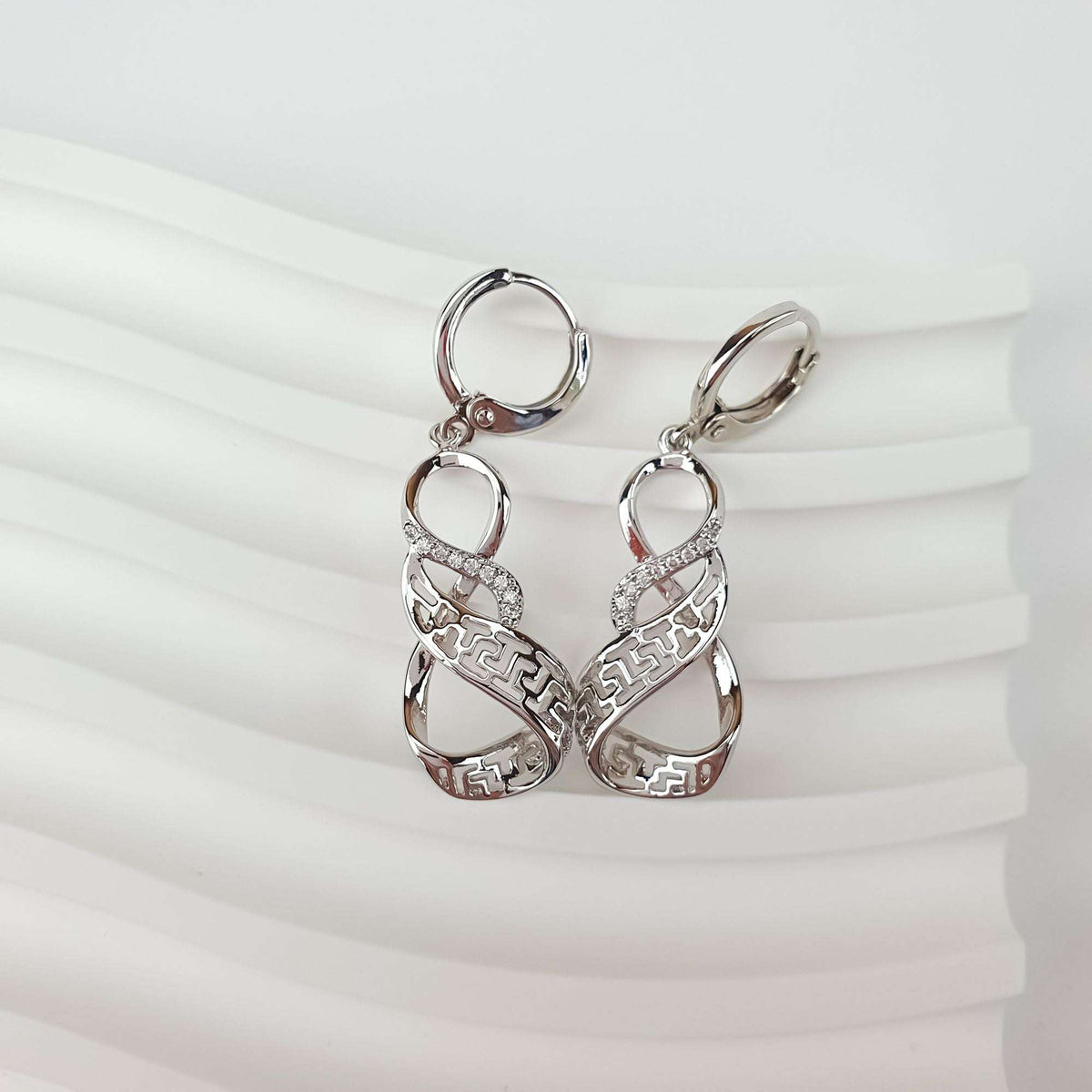 Pair of earrings on a wavy background showing French hooks and a zirconia band