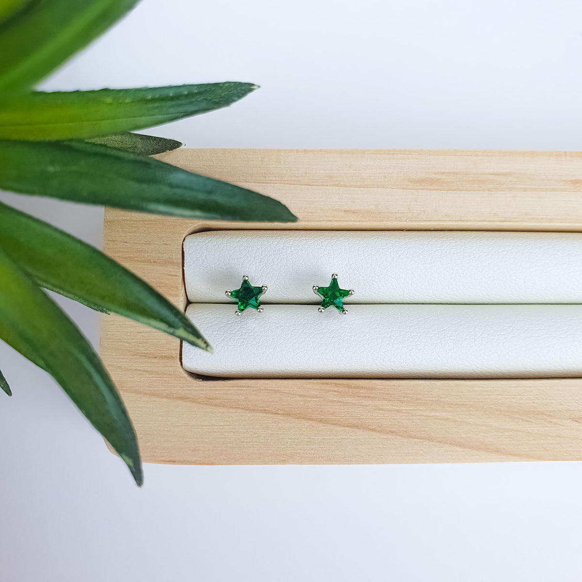 Green star studs on a pale leather jewellery tray
