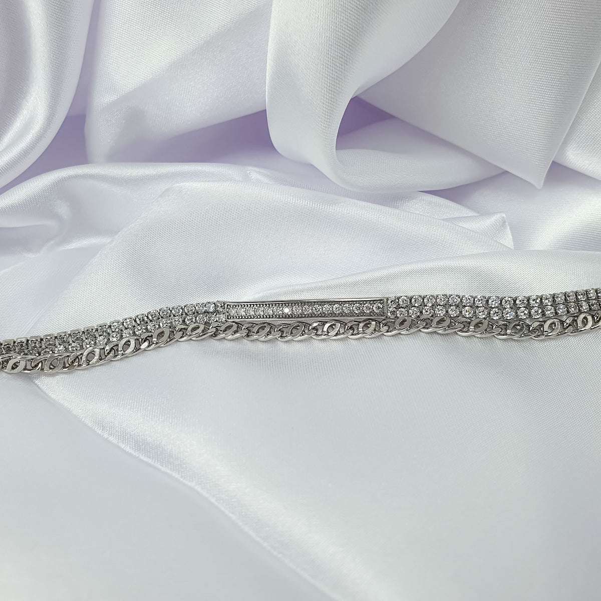 Sparkling cubic zirconia bracelet with chain links and a stone band on white satin