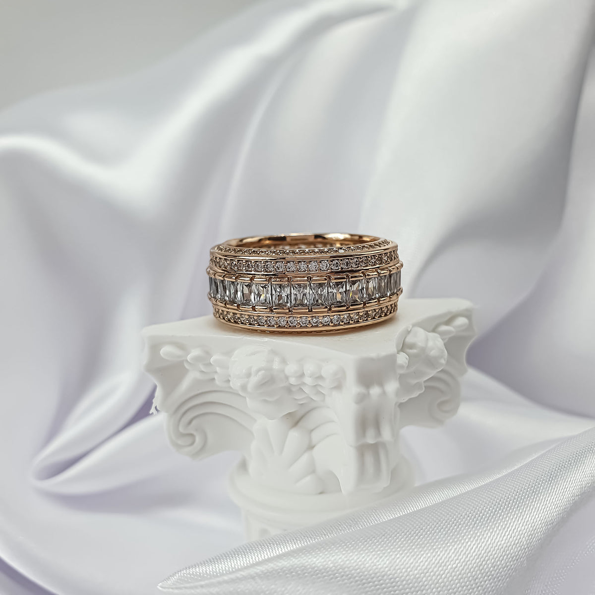 Gold-tone cubic zirconia ring on a white column, fine rows of sparkling stones