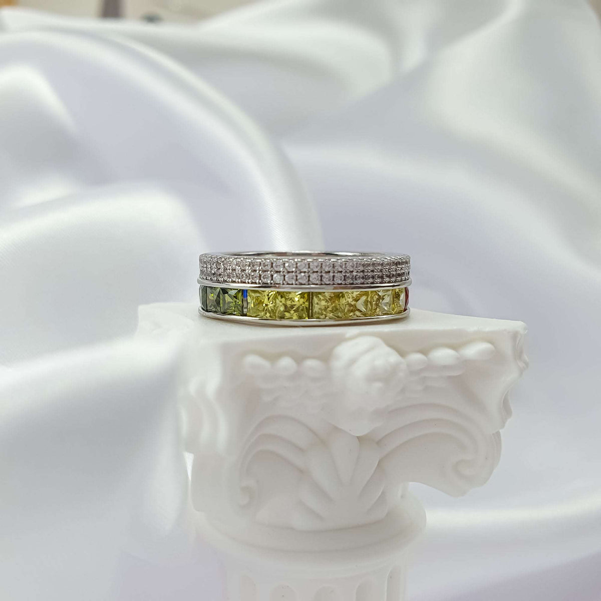Silver-tone ring close-up with a row of yellow and olive green square stones