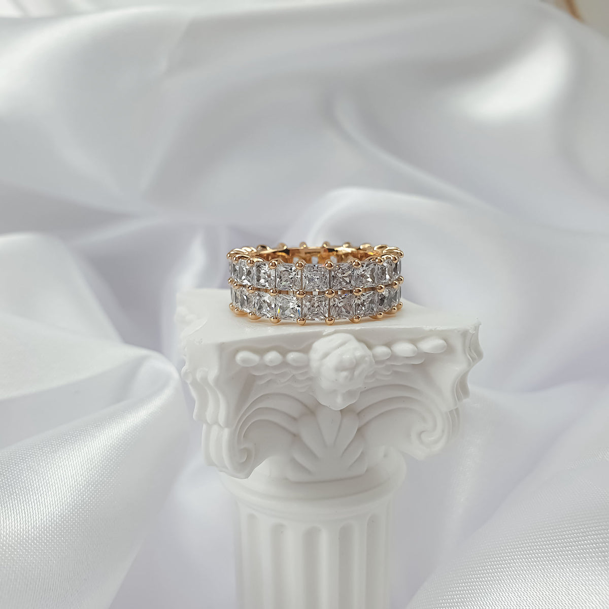 Two-row cubic zirconia ring, front view on a white column