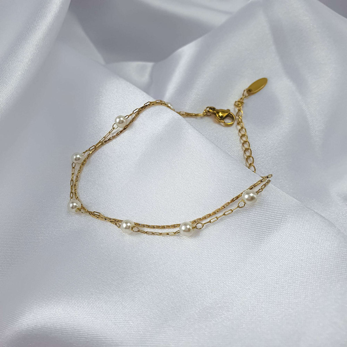 Delicate two-strand bracelet with small pearls and gold-tone chains on white silk