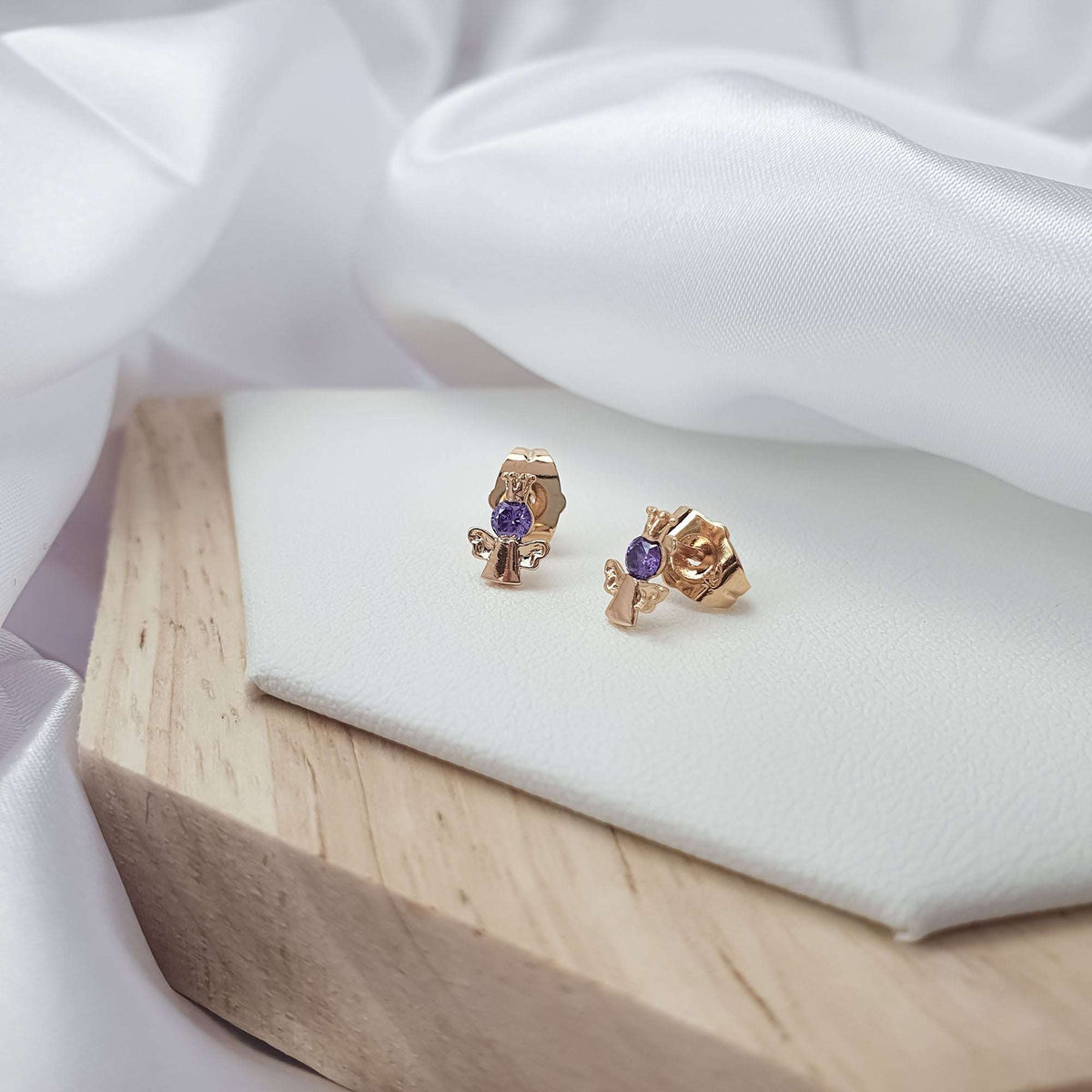 Angel earrings on a light surface, showing push-back posts and violet stones