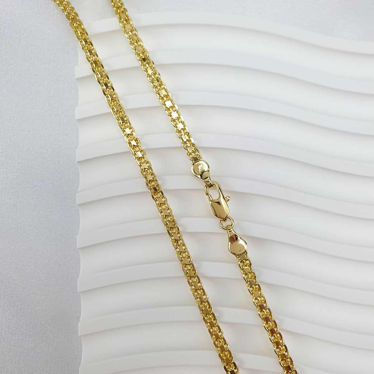 Gold-tone Bismarck chain on a light wavy base, dense link texture visible