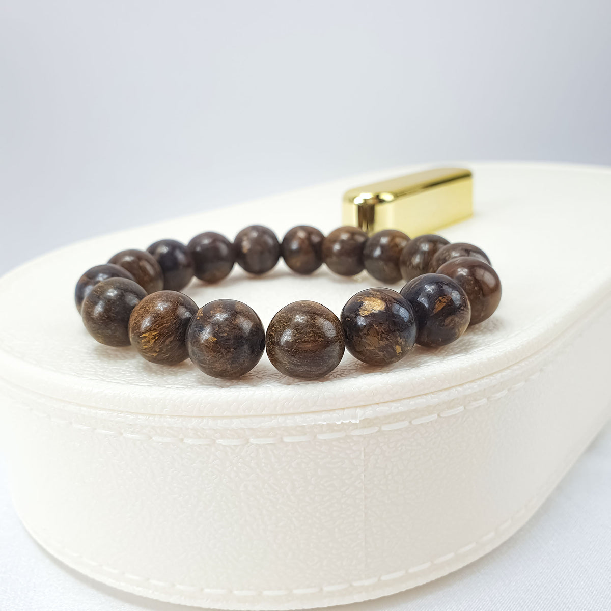 Bronzite bracelet on a white box, polished beads shining golden brown