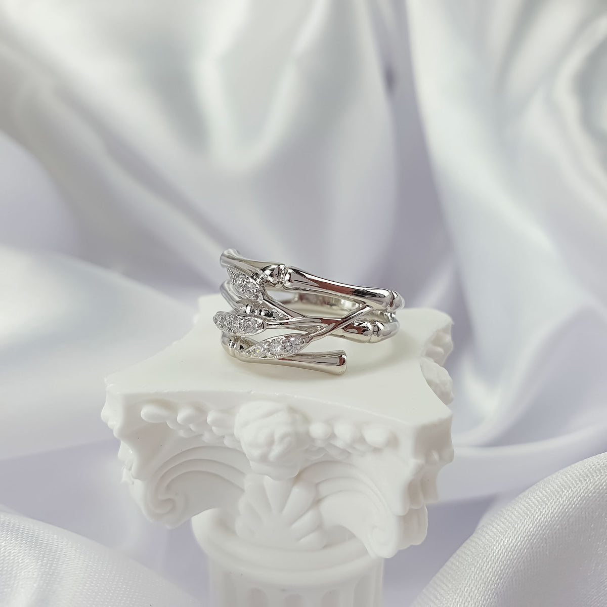Bamboo branch ring with zirconia, side view on a white decorative stand