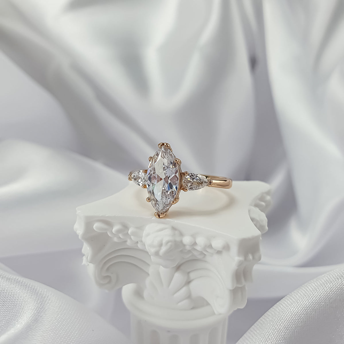Three-stone ring with a marquise centre stone on a white column stand