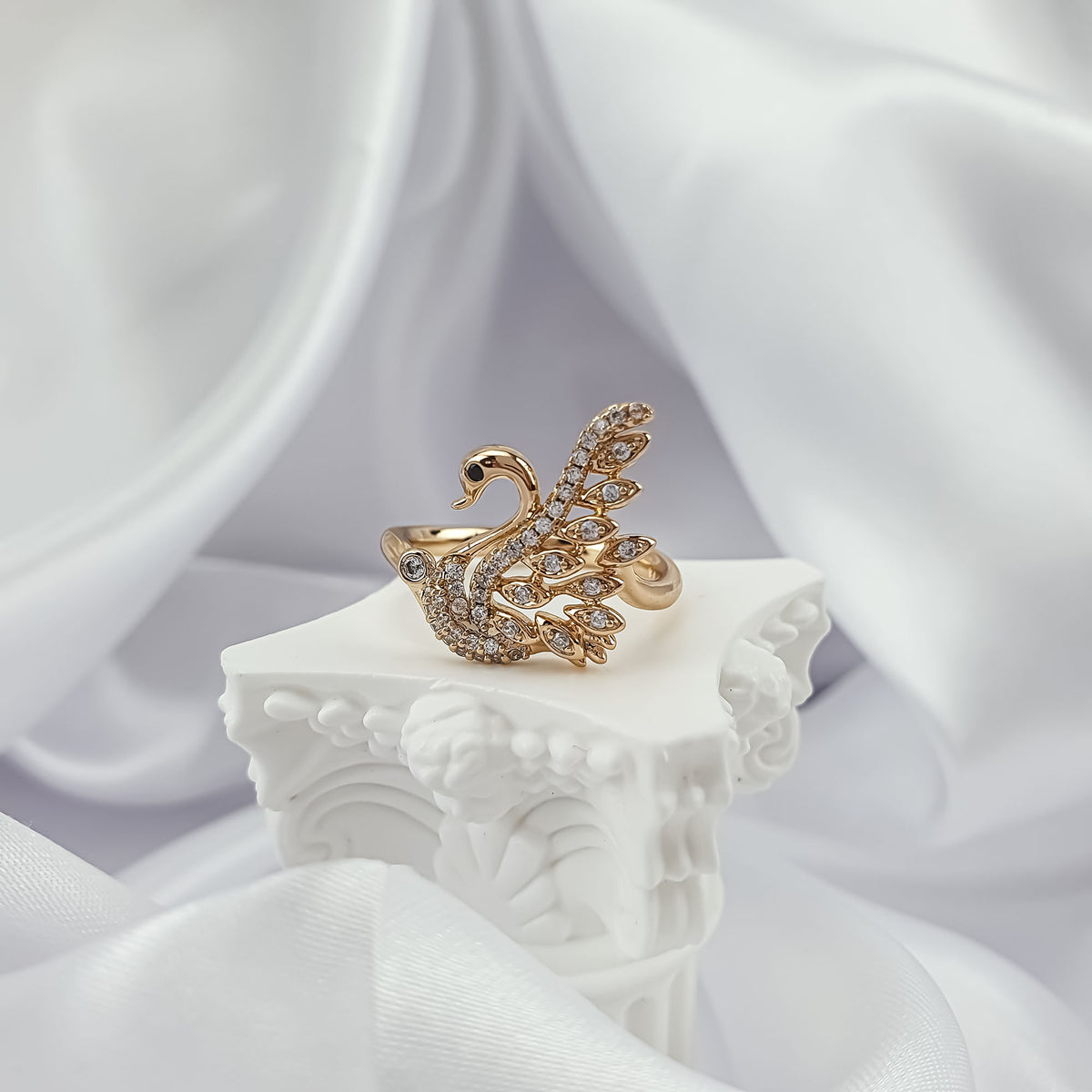 Gold-plated swan ring with cubic zirconia on a white plaster stand
