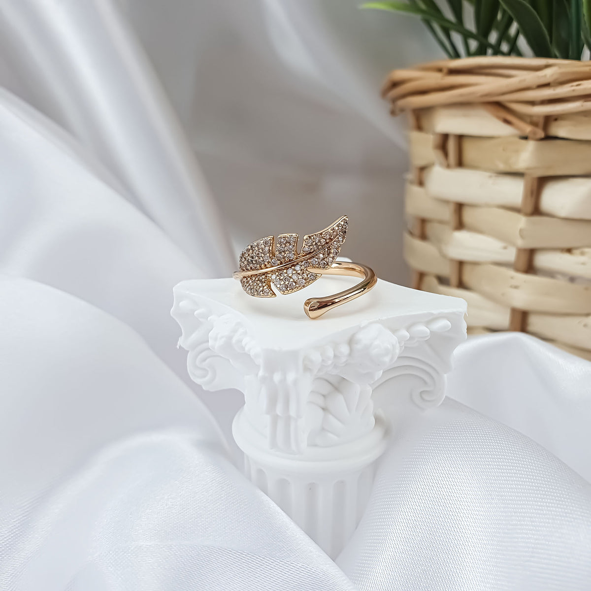 Open gold-plated ring with a stone-set leaf on a light column