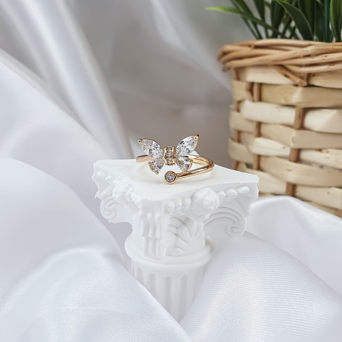 Gold-plated butterfly ring with stone wings on a white column