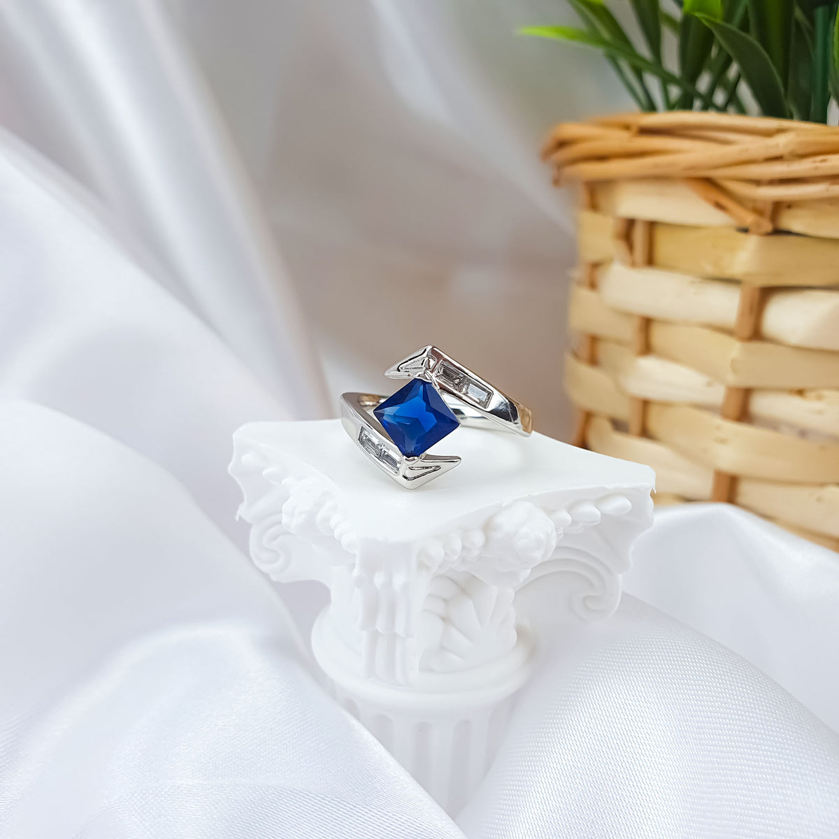 Asymmetric silver-tone ring with a blue square stone on a column