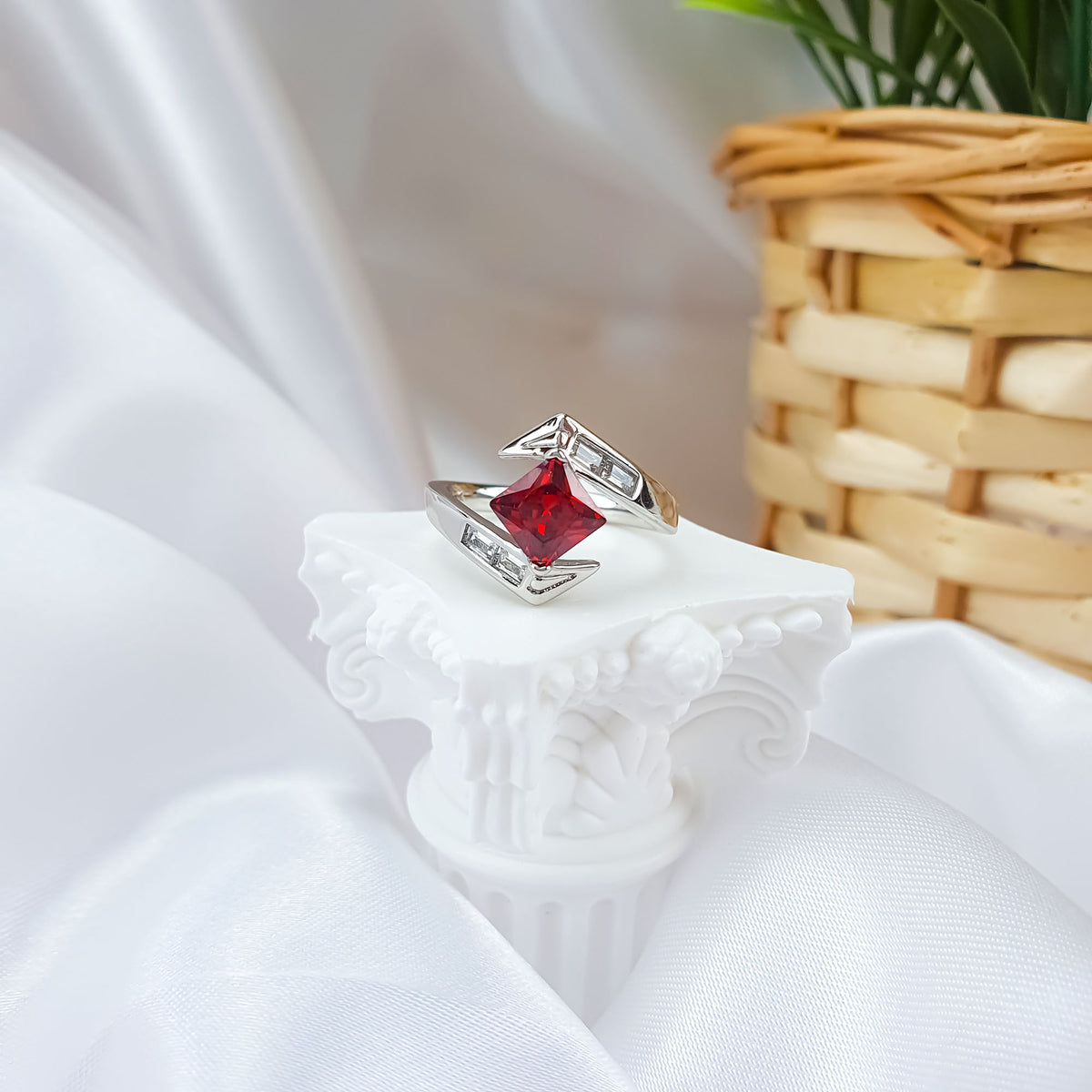 Red stone ring with clear rectangular stones on a white column