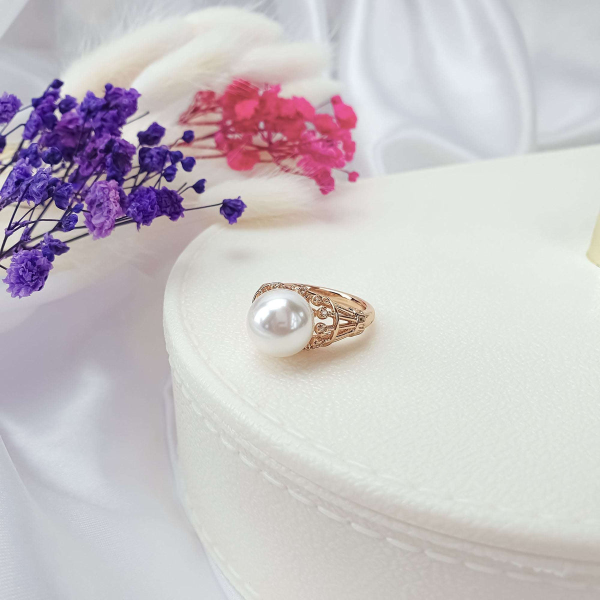 Ring with a large white pearl-like stone in an openwork setting on a box